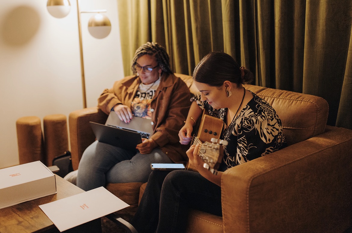 A songwriter playing guitar in a living room